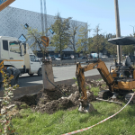 По газону едет экскаватор