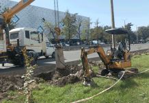 По газону едет экскаватор